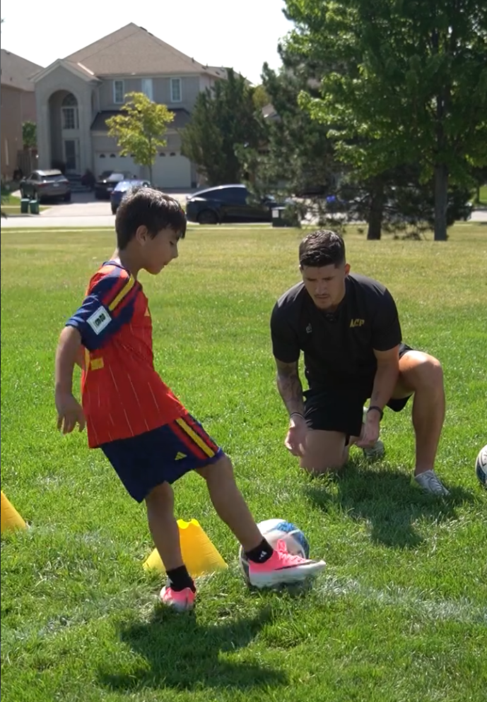 Coach Luca guiding a player through a dribbling drill